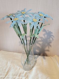 a glass vase filled with blue flowers on top of a white cloth covered tablecloth