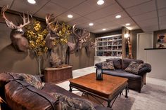 a living room filled with furniture and deer heads on the wall