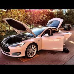 an electric car with its hood open on the street