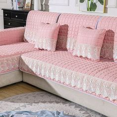 a couch with pink and white pillows on top of it in a living room next to a rug