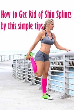 a woman standing on a bridge with her leg in the air and holding a pink skateboard