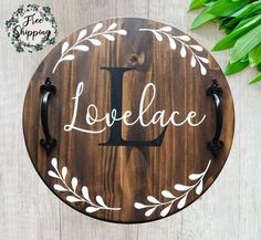 a wooden plaque with the word lovelace painted on it and a plant behind it