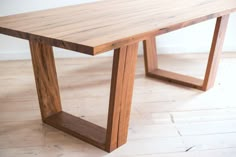 a wooden table sitting on top of a hard wood floored floor next to a white wall