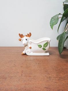 a ceramic figurine of a faucet with leaves on it sitting next to a potted plant