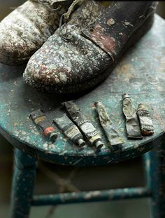 an old pair of shoes sitting on top of a blue stool next to other items