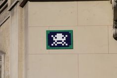 a blue and green sign on the side of a building with a skull in it