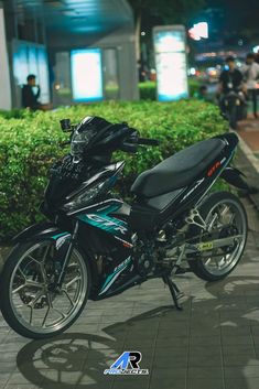 the motorcycle is parked on the side of the road near bushes and people walking by