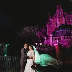 a bride and groom standing in front of a castle at night