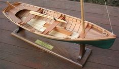 a model boat on display on a wooden floor next to a plaque that reads,