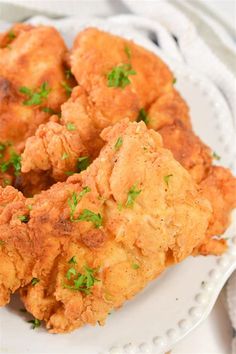 some fried food on a white plate with parsley sprinkled around it's edges