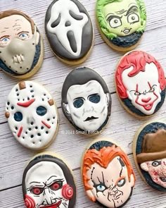 cookies decorated to look like halloween characters are arranged on a white table with wooden boards