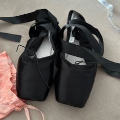 two pairs of black ballet shoes next to a pink dress