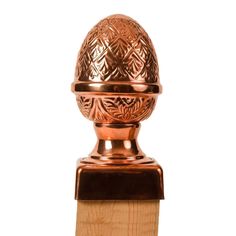 an ornately decorated copper knob on a wooden post