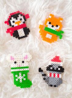 four perler bead christmas ornaments on a white furnishing area, with one cat and the other dog