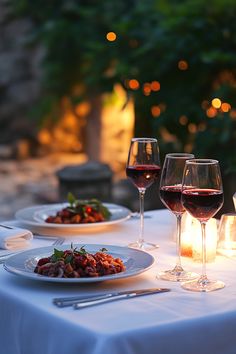 two glasses of wine and plates of food on a table