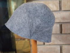 a gray hat sitting on top of a wooden pole next to a brick wall and window