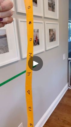 a person holding up a tape measure in front of a wall with pictures on it