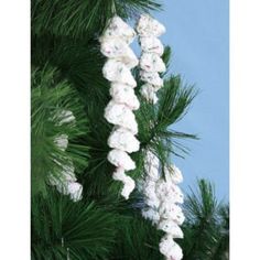 white crocheted ornaments hanging from a pine tree with blue sky in the background