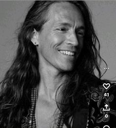 a man with long hair smiling at the camera