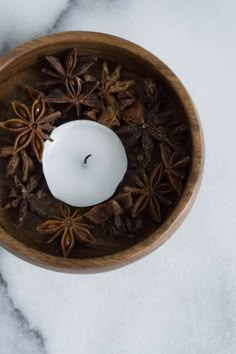 an arrangement of spices in a wooden bowl with a lit candle