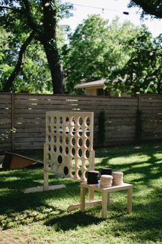 a wooden chair sitting in the grass next to a table with cups on top of it