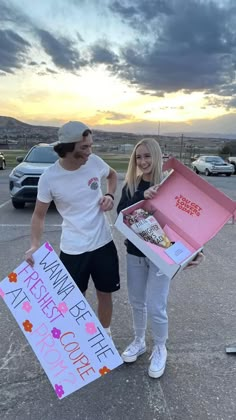 a man and woman standing next to each other holding an open box