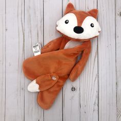 an orange stuffed animal laying on top of a white wooden floor next to a tag