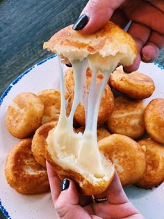 a person is dipping cheese on some fried doughnuts with icing over them