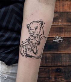 a man with a tattoo on his arm holding a teddy bear