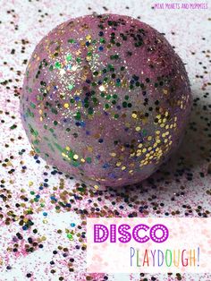 a purple disco ball sitting on top of a pink and gold table cloth with the words disco playdouh