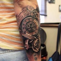 a person with a clock and roses tattoo on their arm is holding a cell phone