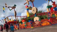 people are walking around an amusement park with many rides and decorations on the sides of them