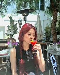 a woman with red hair holding a drink in her hand and looking at the camera