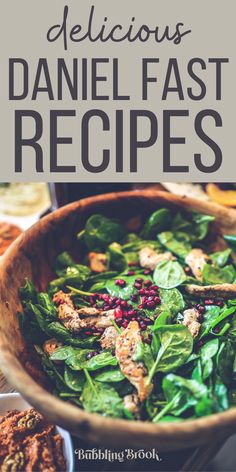 a wooden bowl filled with spinach and other food on top of a table next to bread