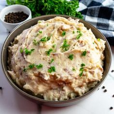 a bowl filled with mashed potatoes on top of a table next to some parsley