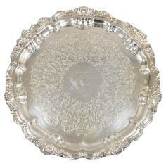 an antique silver plate with ornate designs on the rim and sides, set against a white background