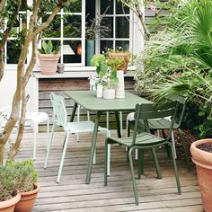 a table and chairs on a wooden deck surrounded by potted plants