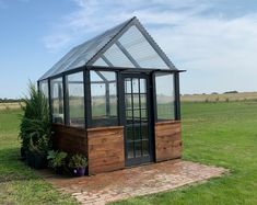 a small wooden greenhouse in the middle of a field