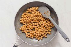 chickpeas are being cooked in a frying pan with a spoon on the side