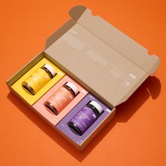 an open box with four different types of hair care products in it on an orange background