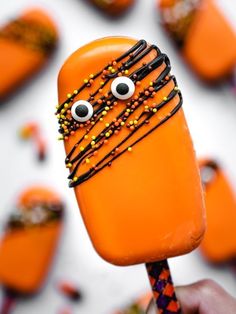 an orange popsicle with chocolate and sprinkles on it, decorated to look like a monster