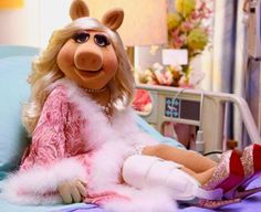 the miss piggy doll is sitting on her bed