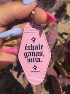 a person holding a pink keychain with writing on it and some nail polish