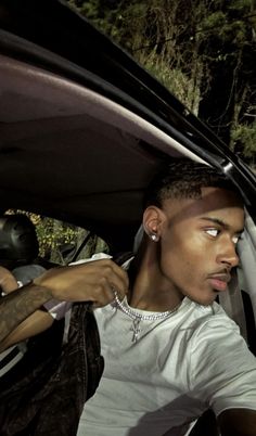 a man sitting in the passenger seat of a car with his hand on the door handle