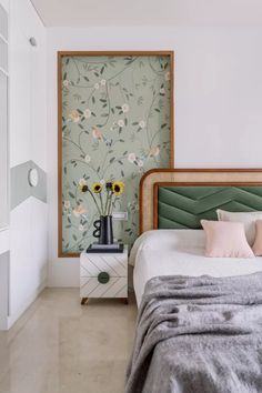 a bed sitting in a bedroom next to a wall with flowers on the headboard