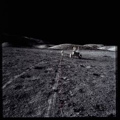 an astronaut walking on the surface of the moon with a vehicle in the distance behind him