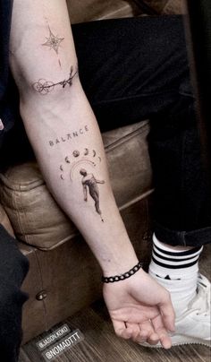 a man with a tattoo on his arm holding the hand of another person who is sitting down