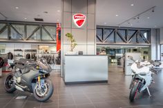 two motorcycles are parked in a showroom next to each other and there is a sign on the wall