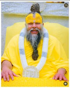 a man with long hair and a beard wearing a yellow outfit sitting on a bench