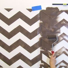 a person painting a wall with brown and white chevrons